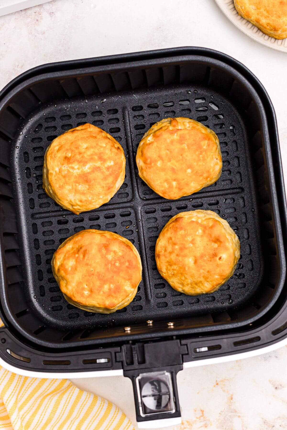 Golden biscuits in the air fryer basket after being air fried. 