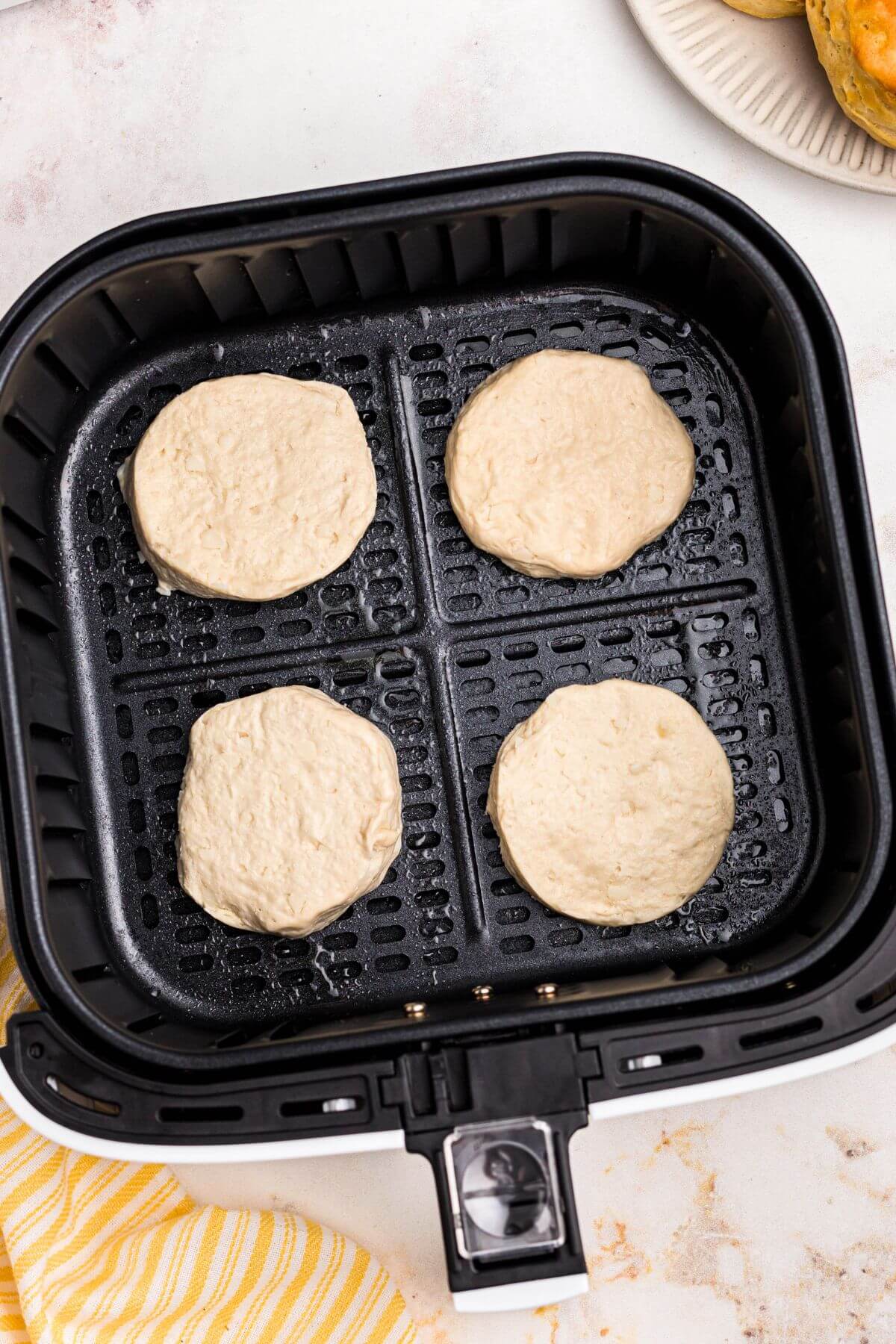 Uncooked biscuit dough in the air fryer basket. 