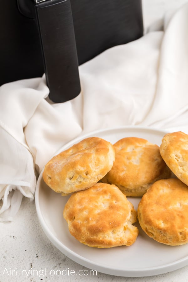 cooked air fryer biscuits on a white plate ready to serve. 