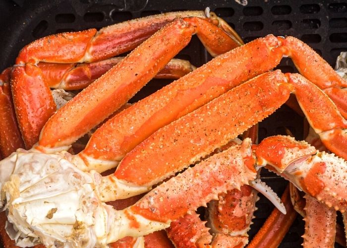 Moist orange close up photo of crab legs, with seasonings, after being cooked in the air fryer. 
