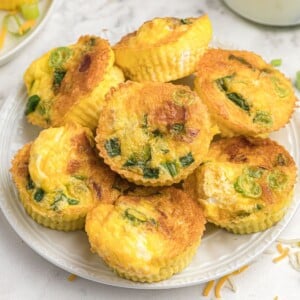 Close up photo of egg bites stacked on top of a white plate.