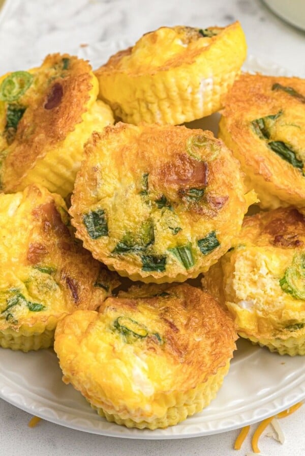 Close up photo of egg bites stacked on top of a white plate.