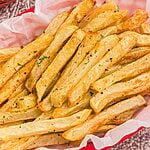 Golden seasoned fries in a red basket after being cooked in the air fryer.