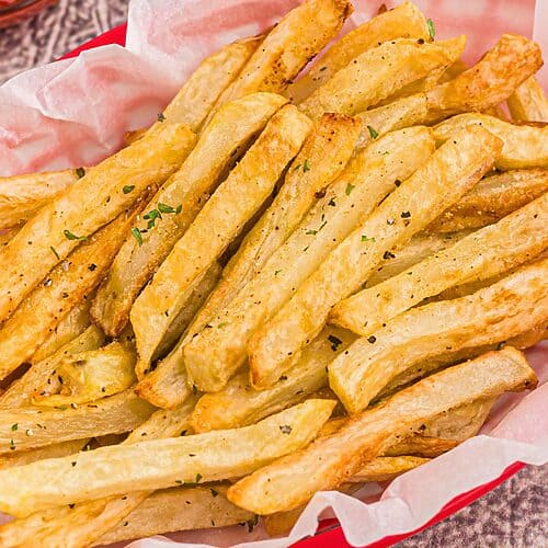 Golden seasoned fries in a red basket after being cooked in the air fryer.