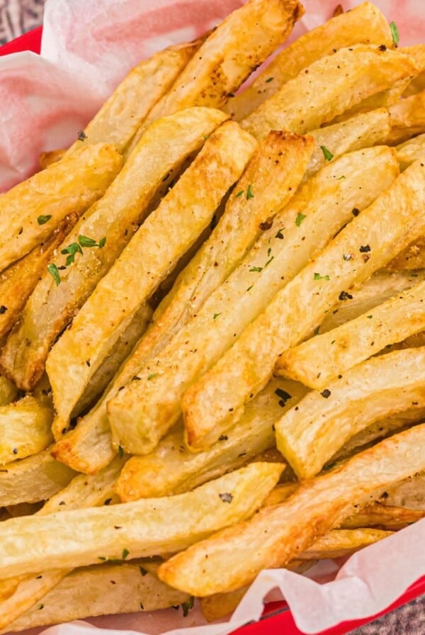 Golden seasoned fries in a red basket after being cooked in the air fryer.