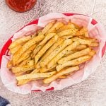 golden crispy french fries in a red basket, served with ketchup.