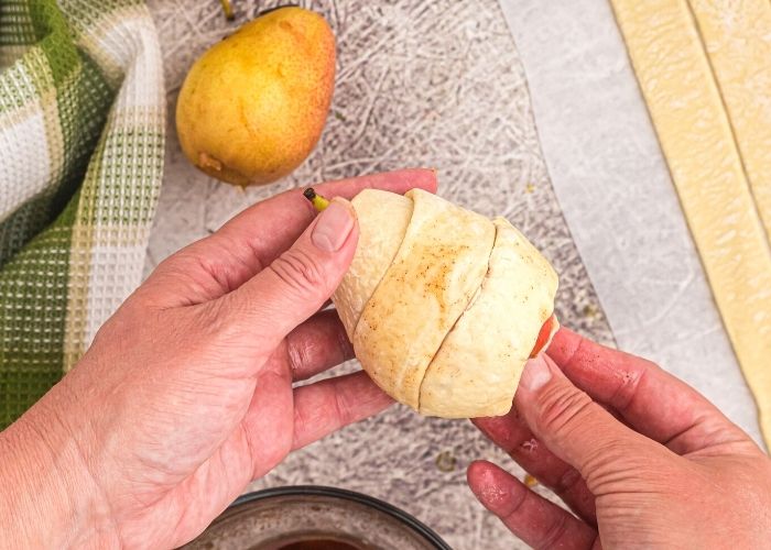 Strips of puff pastry wrapped around a pear, covering it before cooking it in the air fryer. 
