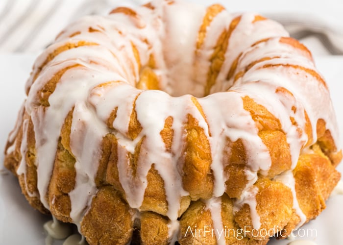 Monkey bread made in the Air Fryer and drizzled with glaze - served on a white plate. 