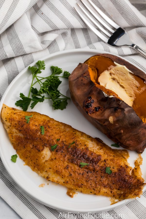 Blackened swai fish made in the Air Fryer on a white plate with a sweet potato on the side. 