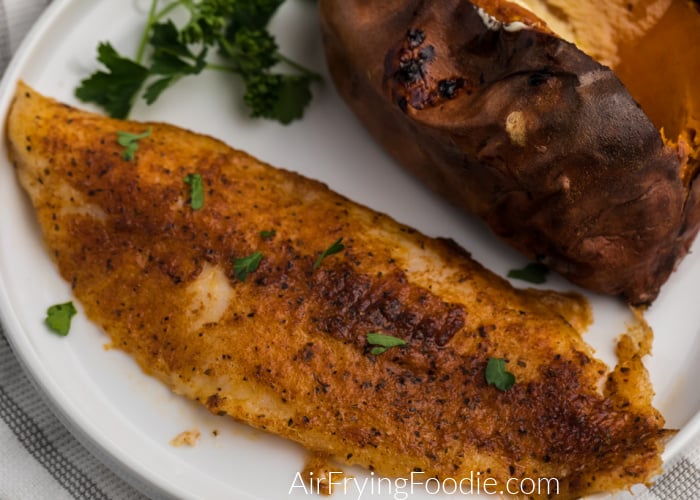 Blackened Swai fish made in the Air Fryer on a white plate with a sweet potato. 