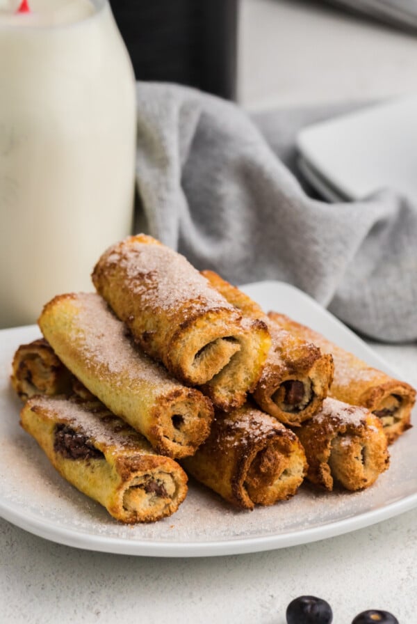 Air Fried Nutella French Toast Roll Ups on a white plate with a glass of milk in the background.