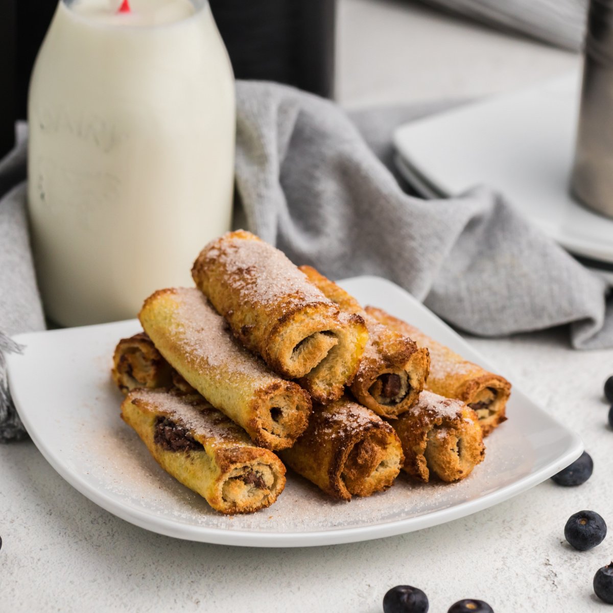 Air Fried Nutella French Toast Roll Ups on a white plate with a glass of milk in the background.