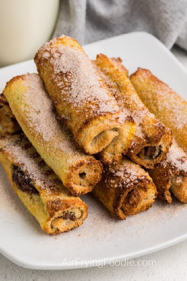 Close up of Nutella stuffed french toast sticks on a white plate and sprinkled with cinnamon and sugar.