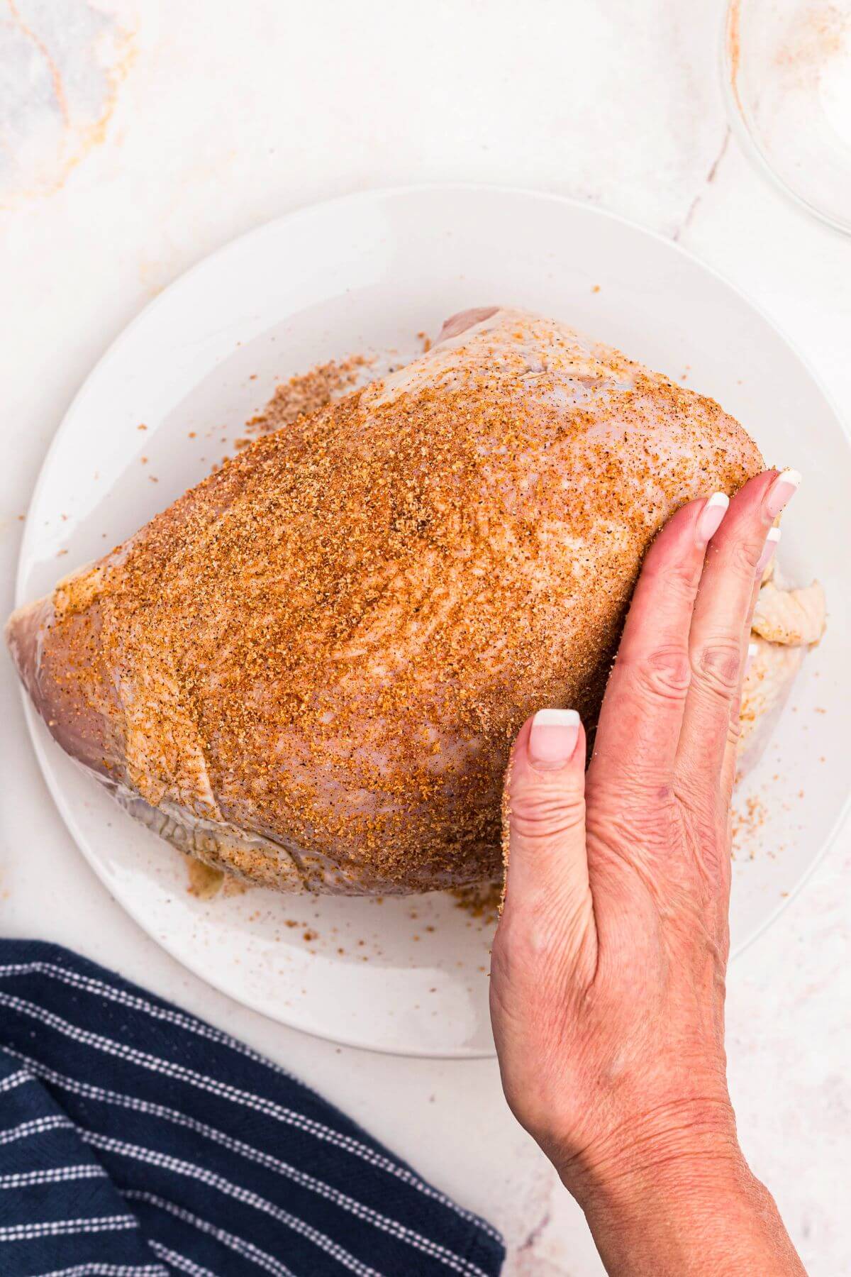 Pressing seasonings onto a turkey breast before cooking. 