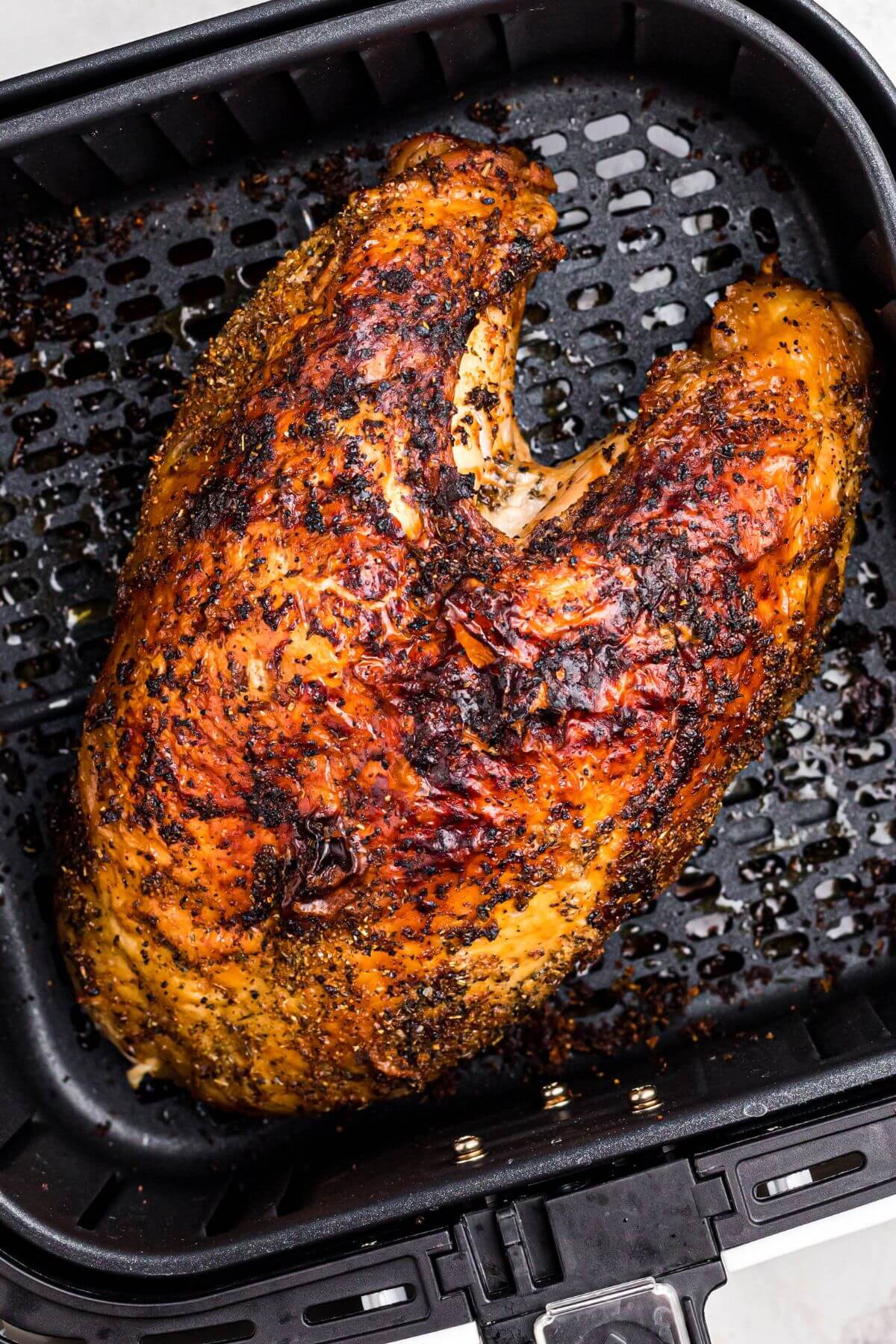 Juicy golden brown seasoned turkey breast in the air fryer basket. 