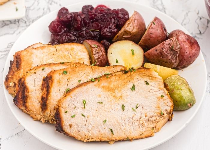 Plated turkey slices served with baby potatoes and cranberry sauce. 