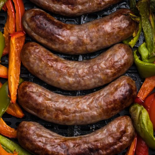 Brats and peppers in the basket of the air fryer.