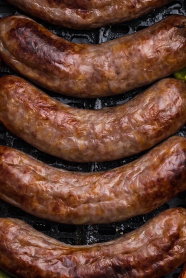 Brats and peppers in the basket of the air fryer.