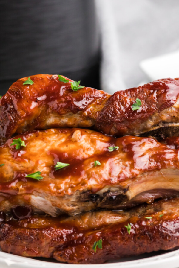 Close up of country style ribs made in the air fryer with the air fryer in the background.