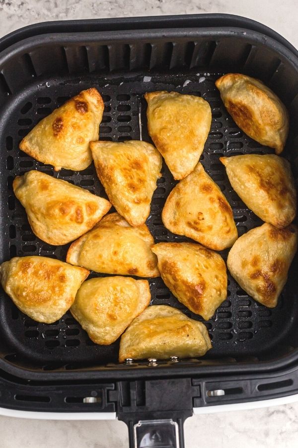 Golden pierogies in the air fryer basket after being cooked. 