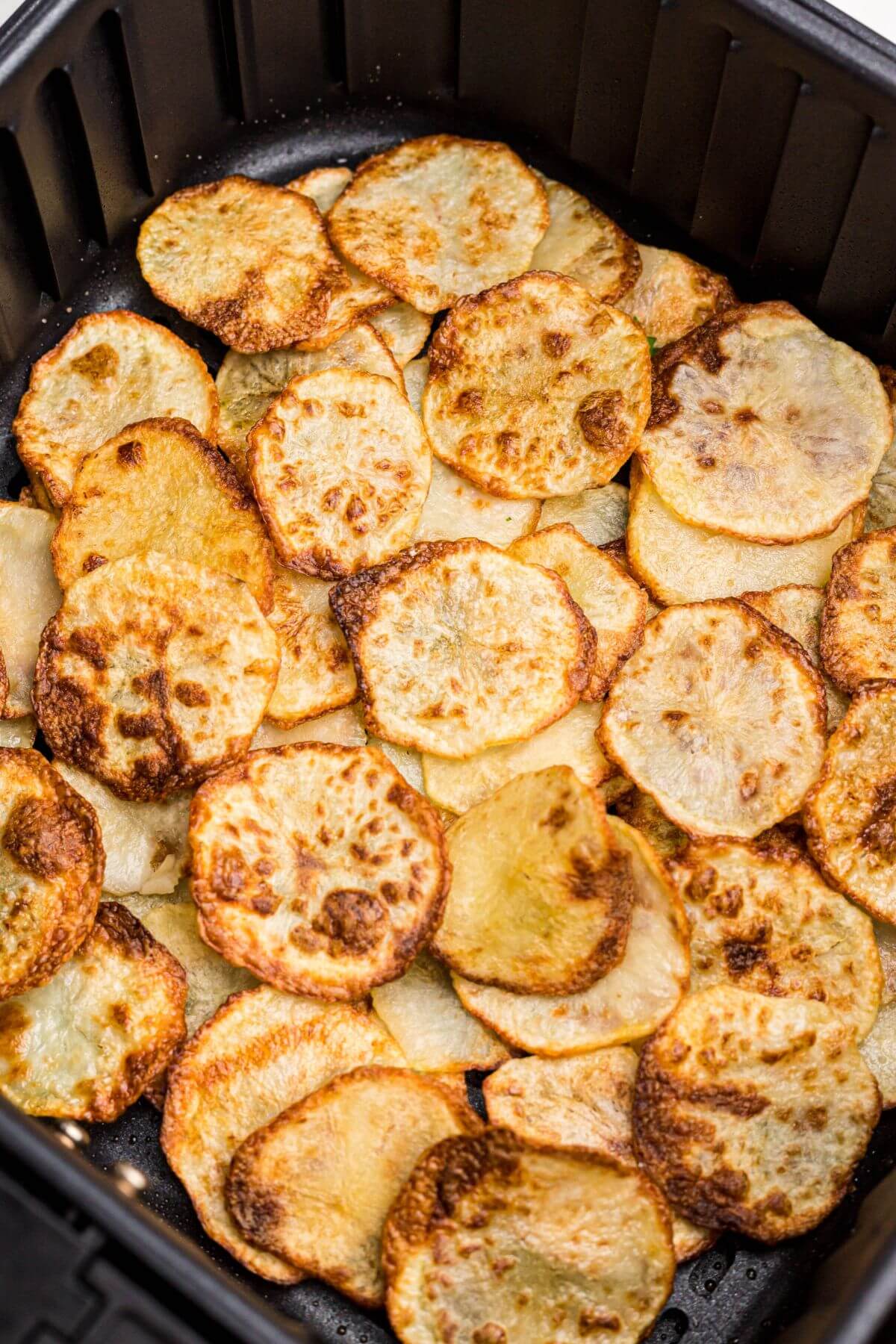 Golden crispy potato chips in the air fryer basket. 