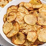 Golden crispy potato chips in a white bowl