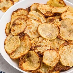 Golden crispy potato chips in a white bowl