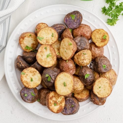 Air Fryer Roasted Potatoes in a white plate and garnished with fresh parsley. Ready to eat.