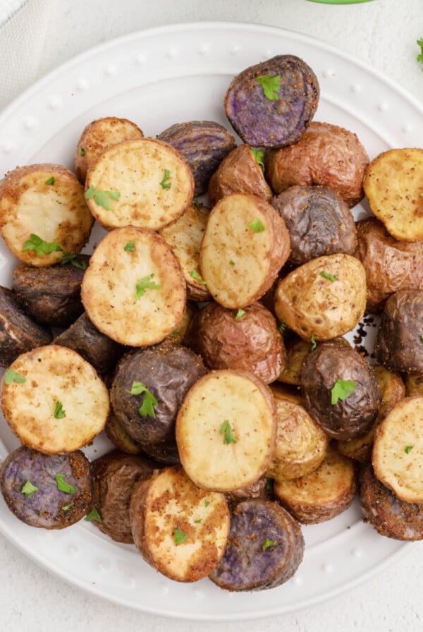 Air Fryer Roasted Potatoes in a white plate and garnished with fresh parsley. Ready to eat.