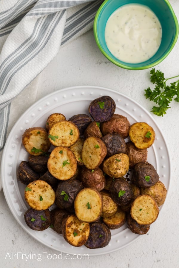 Overhead shot of air fryer roasted potatoes on a white plate topped with fresh parsley. 
