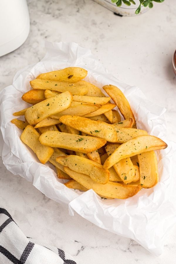 Golden steak fries after being cooked in the air fryer with parsley flakes as a garnish. 