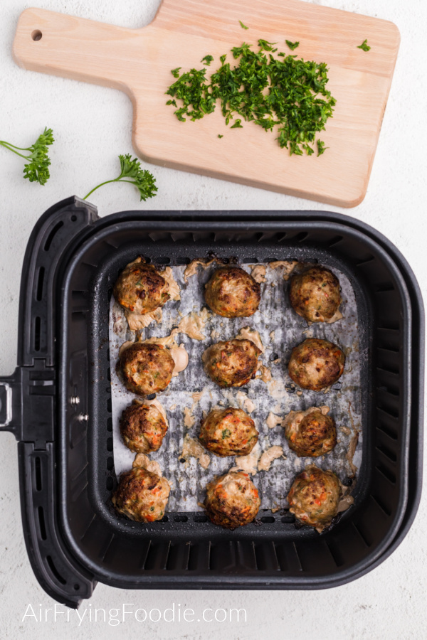 Fully cooked Turkey meatballs in the basket of the air fryer. 