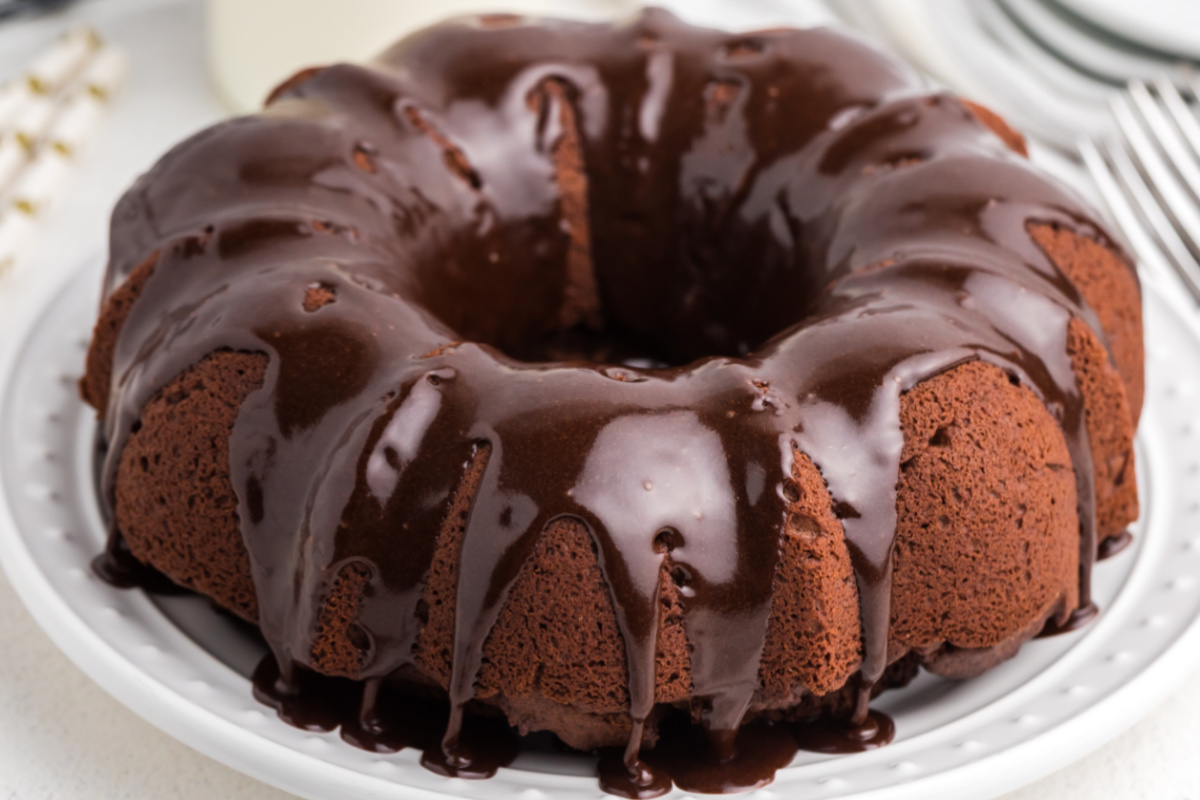 Chocolate bundt cake with chocolate frosting on a white plate. 