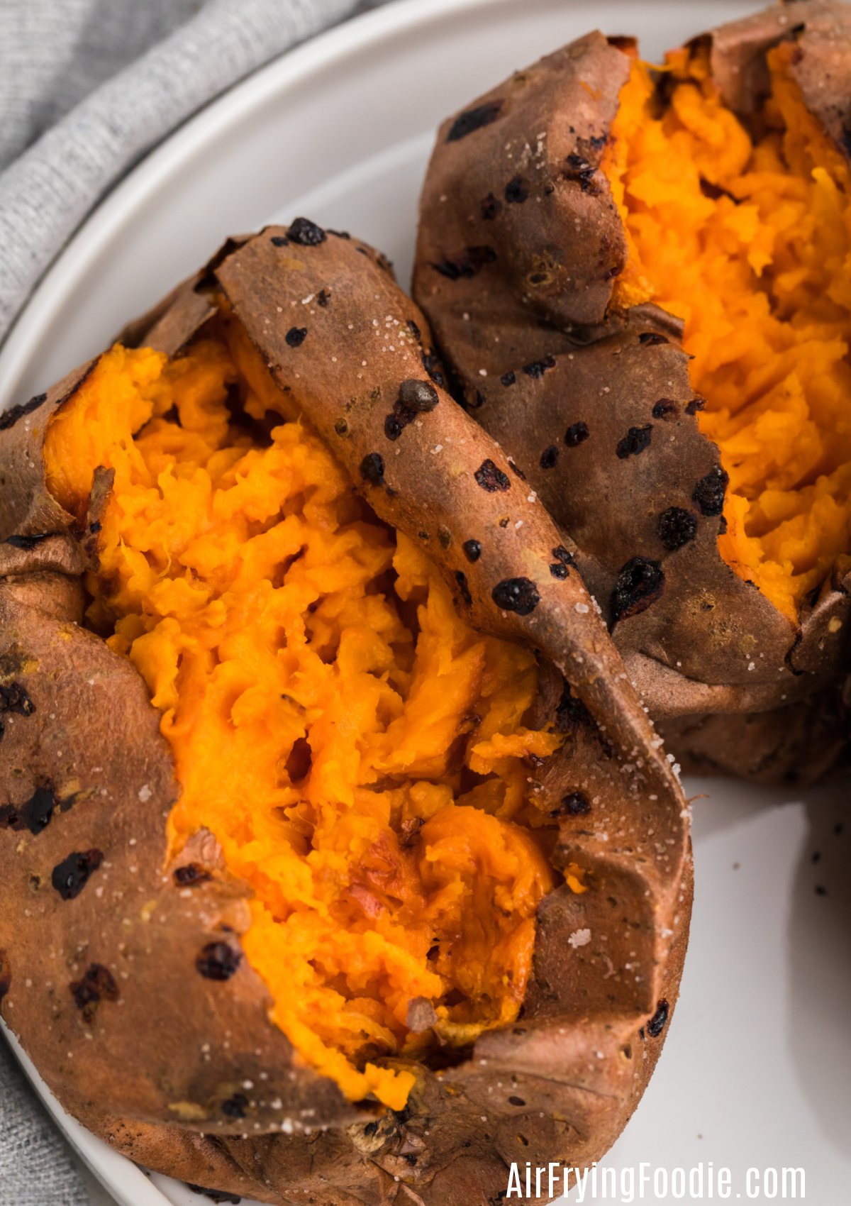 Close up photo of baked sweet potatoes that were made in the air fryer - sliced open and ready for toppings. 