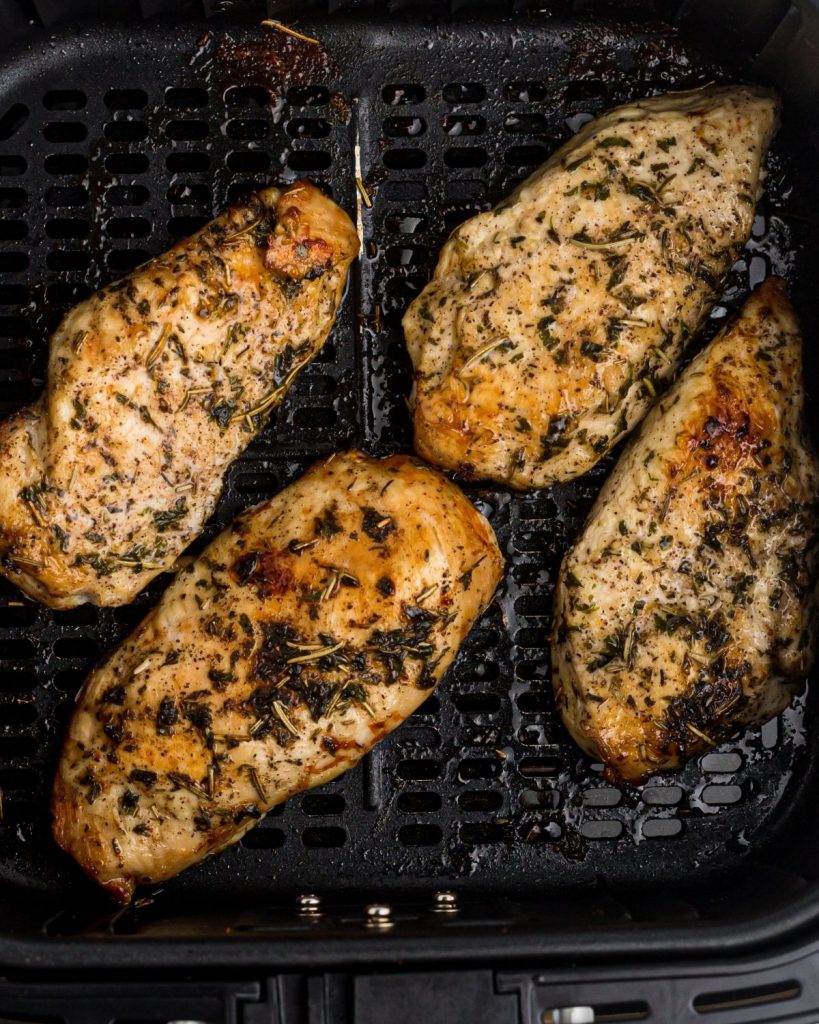 Seasoned and cooked chicken breasts in the air fryer basket. 