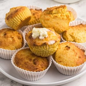 Close up of cornbread muffins with top muffin covered in melting butter.