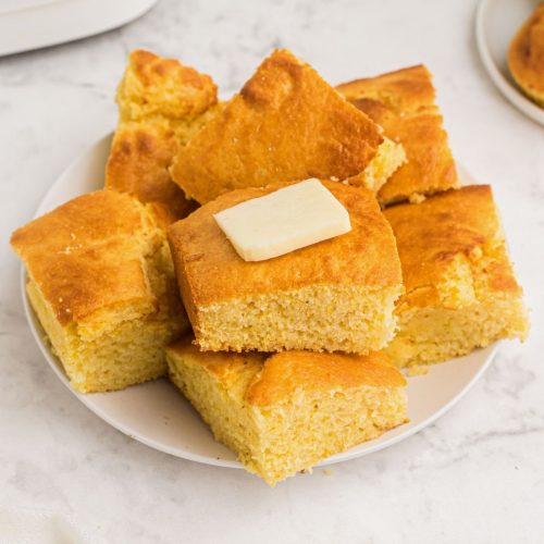 Cornbread on a white plate with butter on top