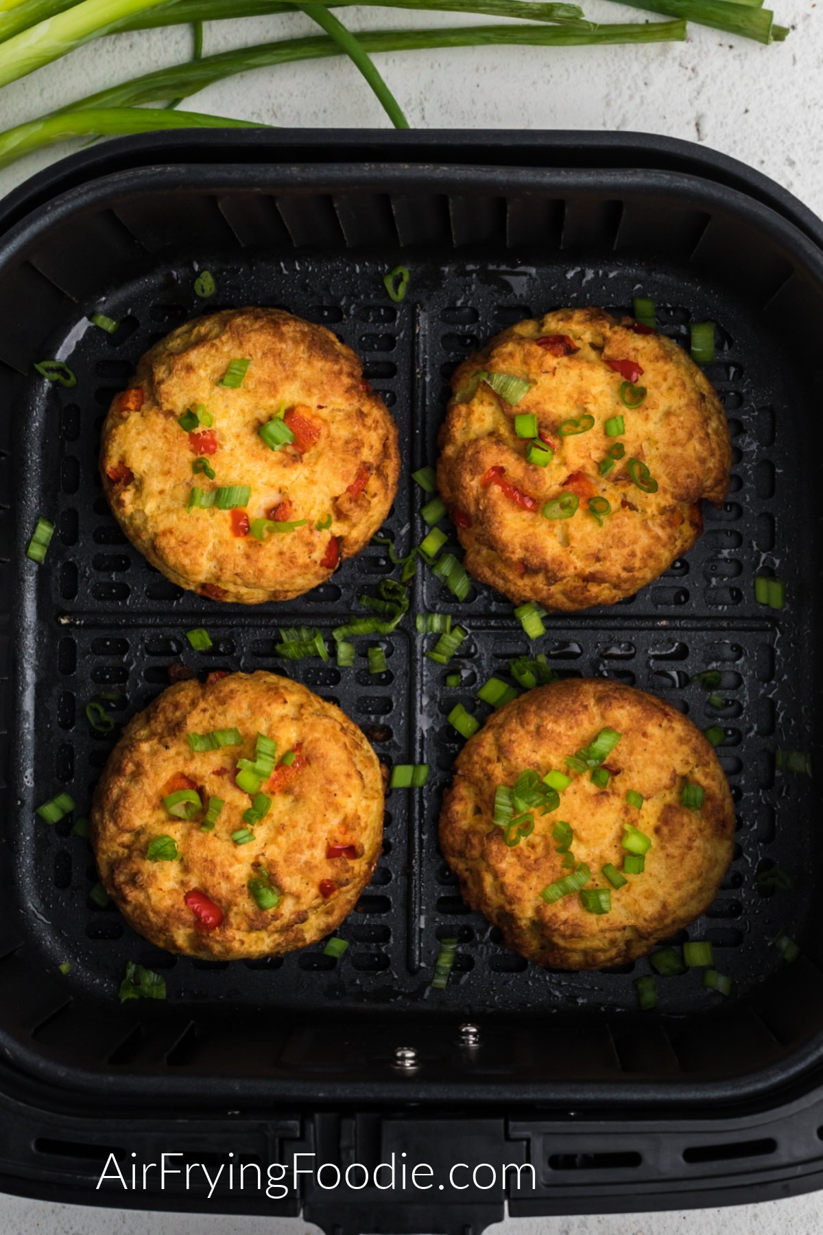 Crab cakes in the air fryer basket fully cooked and ready to serve.