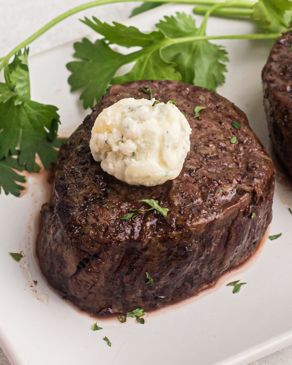 filet mignon on a plate with parsley on the side. 