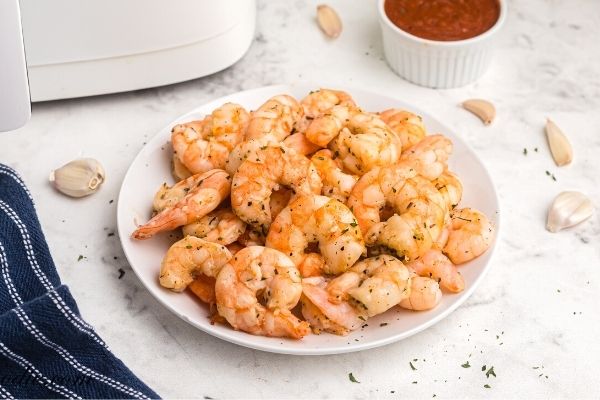 Golden air fryer shrimp, cooked and served on a white plate. 