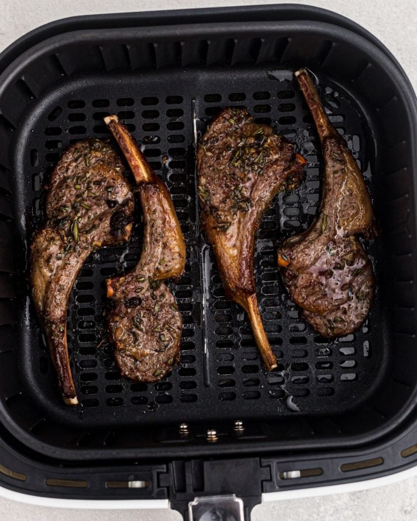 Juicy lamb chops in air fryer basket after being cooked. 