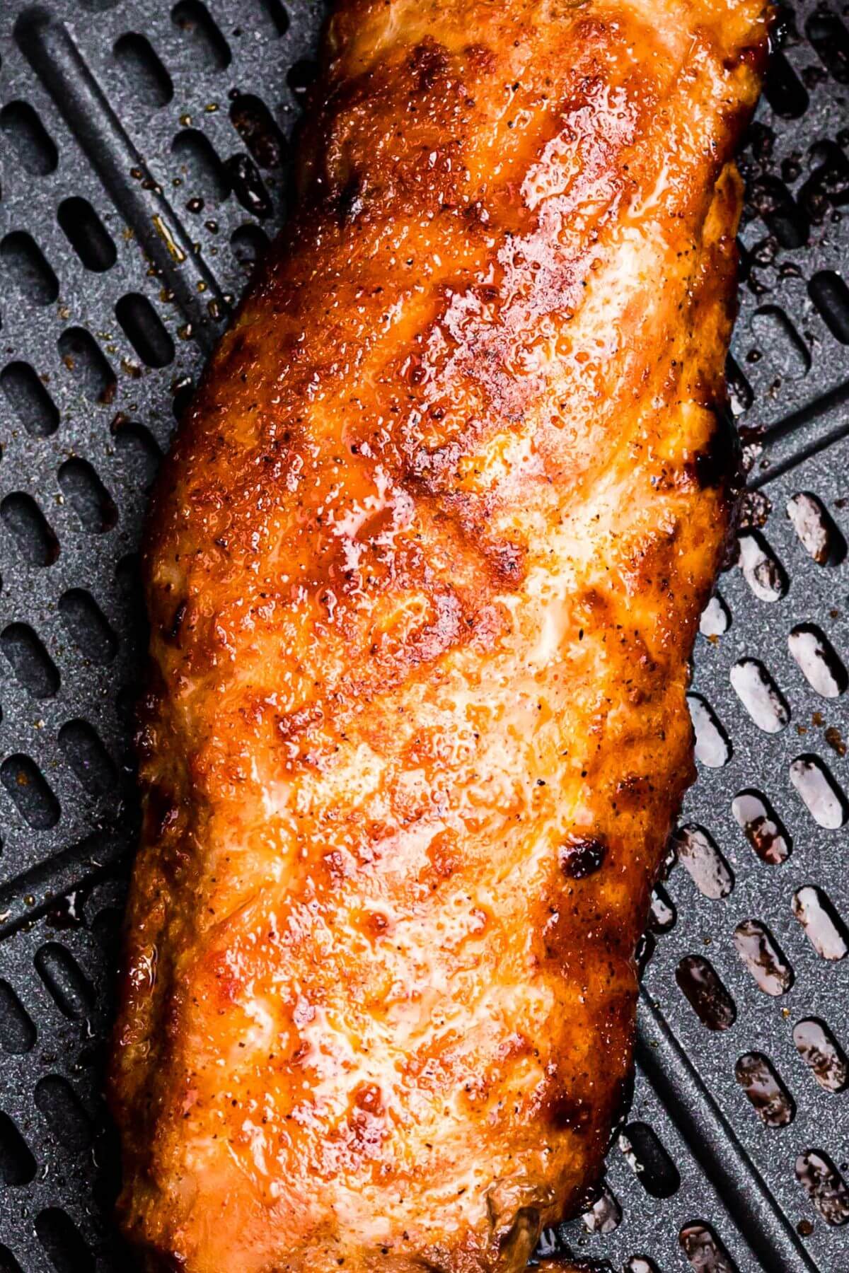 Crispy coated seasoned pork tenderloin in the air fryer basket after being cooked. 