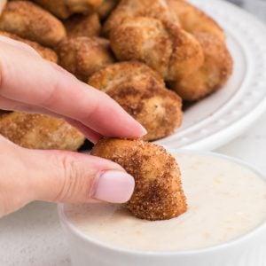 cinnamon sugar pretzel bites being dipped in a sugary glaze dipping sauce.