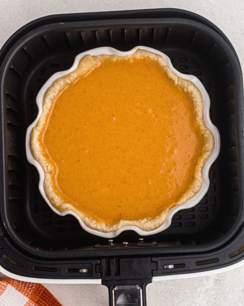 Uncooked pumpkin pie in an air fryer basket. 