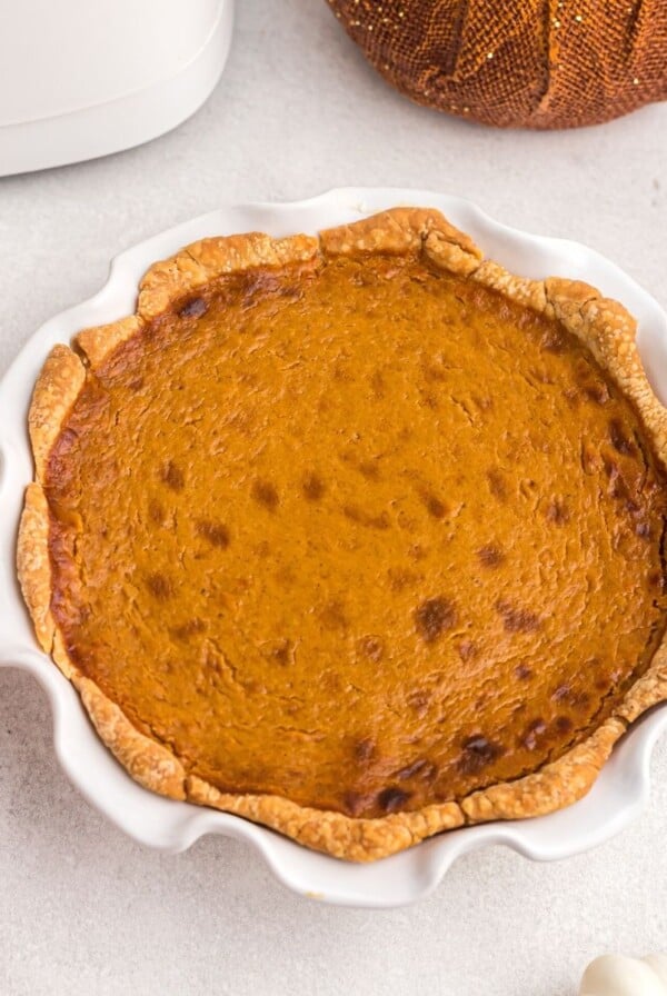 Golden orange pie in a white pie plate after being cooked in the air fryer.