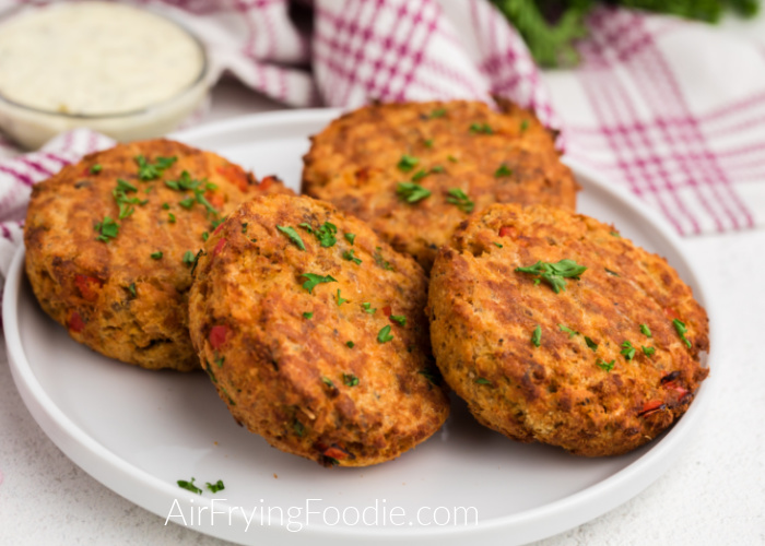 Salmon patties made in the air fryer and served on a white plate - garnished with fresh parsley. 