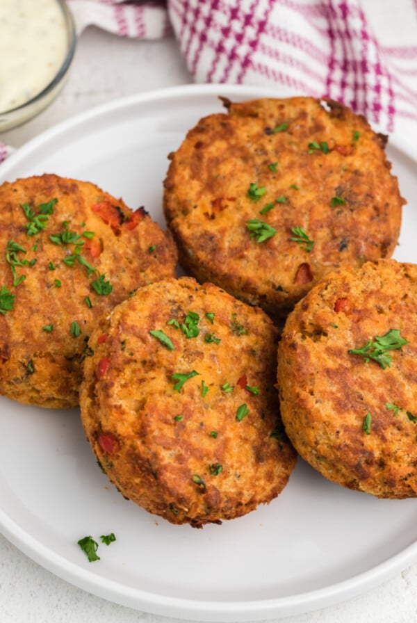 Air Fryer Salmon Cakes on a white plate with dipping sauce on the side.