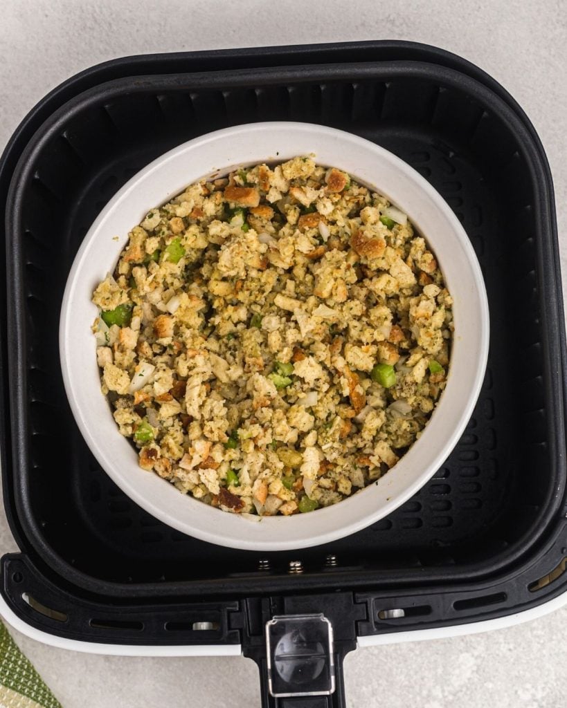 Stuffing mixture combined in a white bowl before cooking in an air fryer basket. 