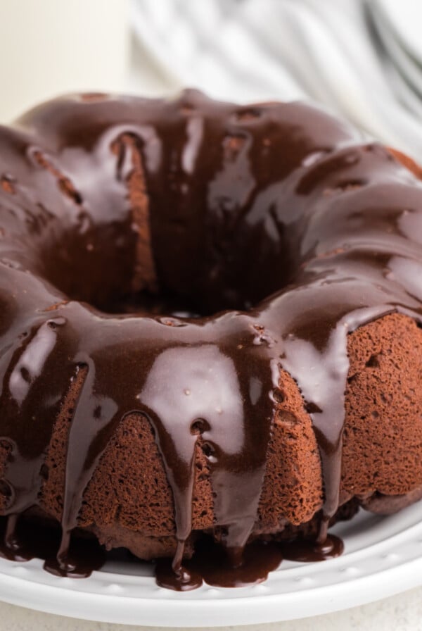 Chocolate Bundt Cake on a white plate and topped with chocolate frosting.