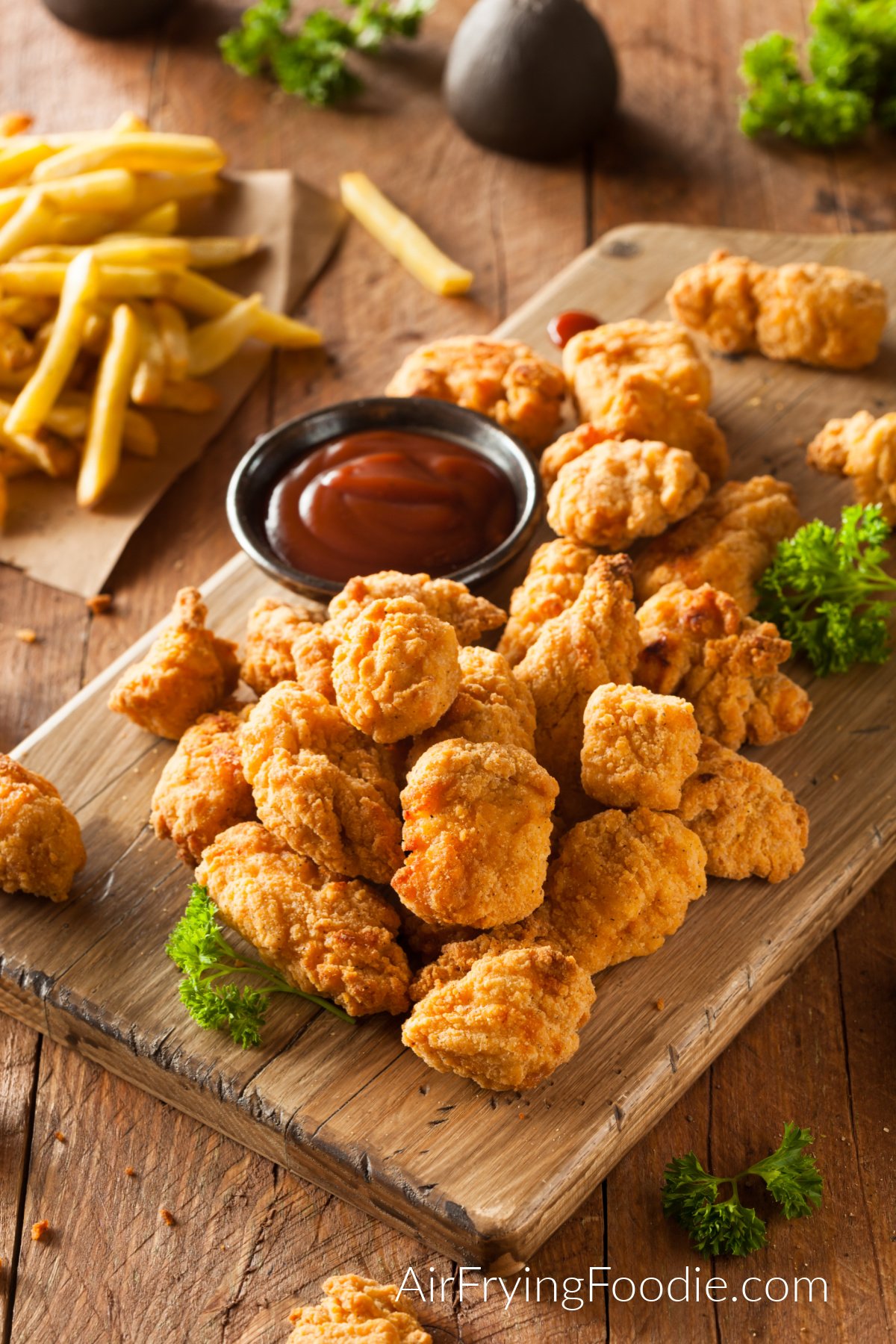 chicken bites on a board with dipping sauce. 